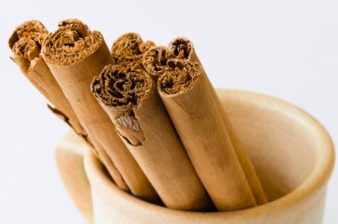 Bir fincan beyaz bir arka plan üzerinde kuru tarçın