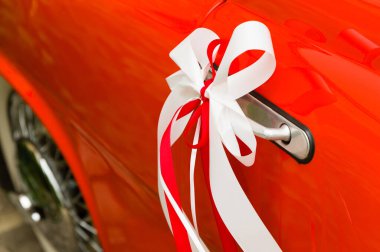 Bir kapı kolu kırmızı bir eski model araba, kırmızı ve beyaz dekoratif düğün şeritler
