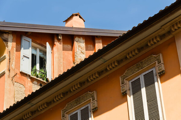 Orange facade of house with wooden window shutters in Bologna