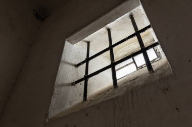 Eski bir hücrede parmaklıklı pencere.