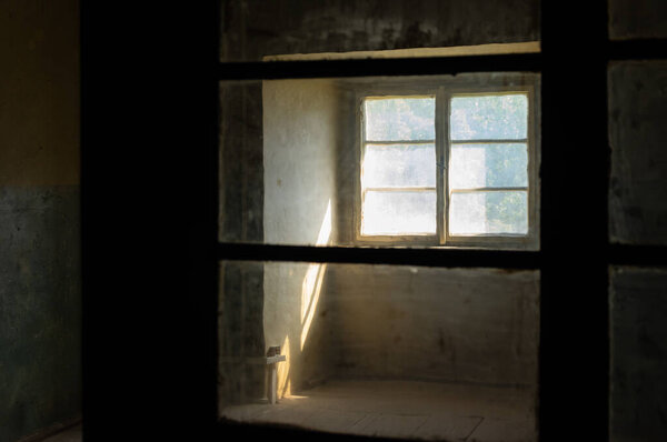 Sunlight entering a dark spooky room through filthy windows in an abandoned house