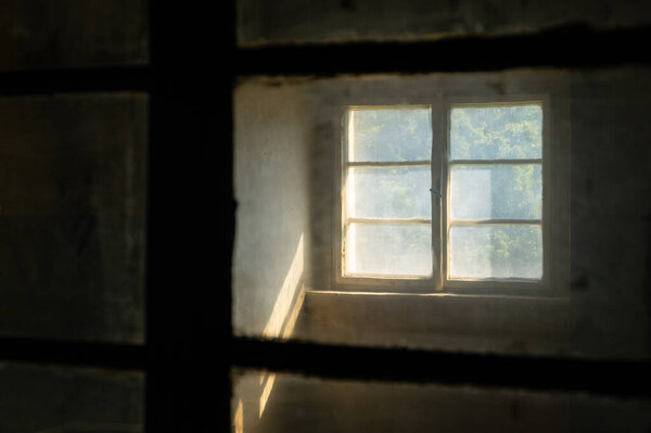 Sunlight entering a dark spooky room through filthy windows in an abandoned house