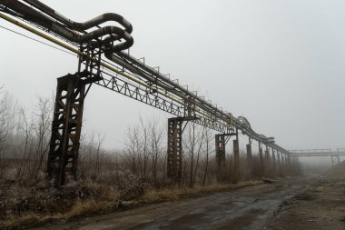 Sisli bir kış gününde terk edilmiş bir sanayi bölgesinde borular ve borular.