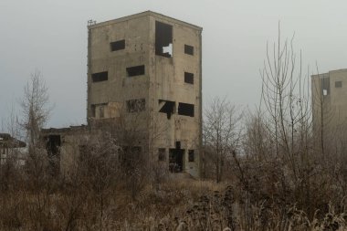 Creepy concrete building in an abandoned industrial area covered in winter fog clipart