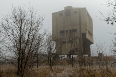 Creepy concrete building in an abandoned industrial area covered in winter fog clipart