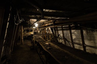 Çek Cumhuriyeti 'nde terk edilmiş bir kömür madeninde havalandırma boruları, kablolar ve kemer taşıyıcısı olan loş bir maden tüneli..