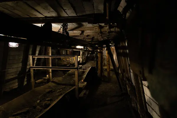 Çek Cumhuriyeti 'nde terk edilmiş bir kömür madeninde havalandırma boruları, kablolar ve kemer taşıyıcısı olan loş bir maden tüneli..