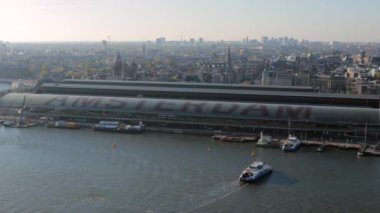 Amsterdam Merkez İstasyonu 'nun ve Hollanda' nın IJ Nehri 'nin havadan bakış açısı. Yüksek kalite 4k görüntü
