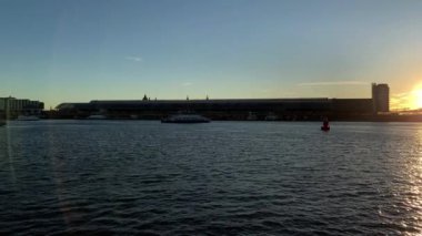 Amsterdam, Hollanda 'da günbatımında IJ nehrindeki modern binalarla Skyline. Döndürme çekimi.