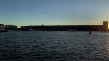 Amsterdam, Hollanda 'da günbatımında IJ nehrindeki modern binalarla Skyline. Döndürme çekimi.