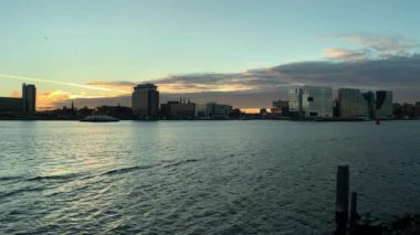 Amsterdam, Hollanda 'da günbatımında IJ nehrindeki modern binalarla Skyline. 