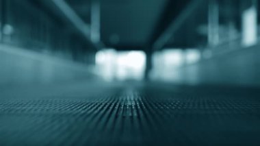 Hollanda havaalanı terminalinde hareket eden travelatördeki insanların düşük açılı görüntüsü.