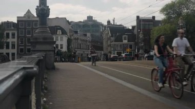 Amsterdam, Hollanda - 20 Mayıs 2023: Şehir merkezinde bisiklet süren insanlarla birlikte şehir sokak manzarası.