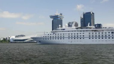 Amsterdam, Hollanda - 26 Mayıs 2023: IJ Nehri boyunca modern mimariye sahip büyük beyaz yolcu gemisi.