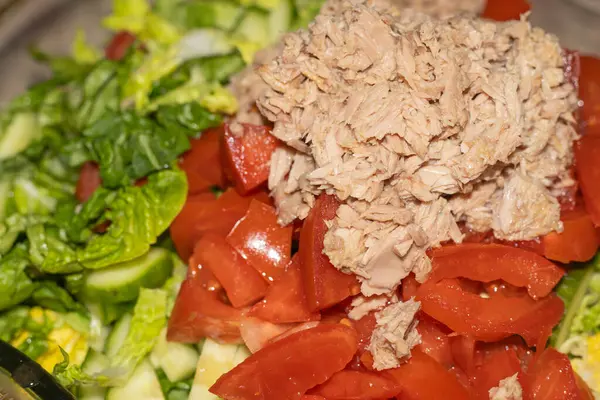 salad from chicken, vegetables and cheese,Tuna salad was invented on the fly.Lettuce, tomatoes and tuna go together perfectly. A picturesque picture of food is created.