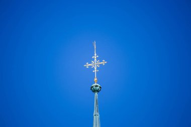 Kilise mavi gökyüzüne karşı eski bir kiliseyi geçiyor. Grafik kaynaklar, tasarım, sanatsal fikirler. Mavi üzerinde altın haç desenleri.