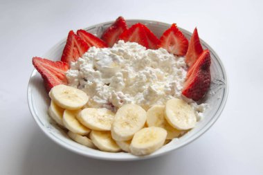 Büyük bir tabak süzme peynir ve meyve kahvaltısı. Sağlıklı bir diyet için sağlıklı bir yemek. Sağlıklı bir kahvaltı süzme peynir, muz ve çileklerden oluşur. Beslenme, bebek maması, ekolojik ürünler.