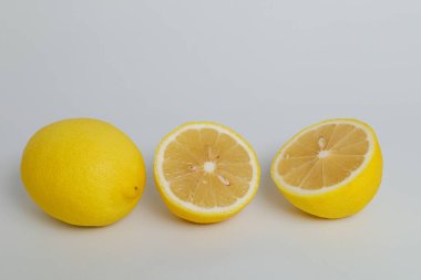 Limon beyaza sabitlenmiş. Beyaz arka planda tam meyve ve yarım limon. Kırpma yolu ile. Tam alan derinliği.