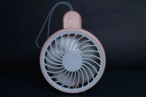 Mini electric pink pan, isolated on dark background. front view. Portable electrical equipment that very useful when hot weather.