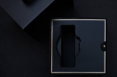 Siyah arka planda altın şeritli boş siyah akıllı kutu. Üst manzara, düz uzanma..