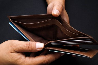 Adam siyah arkaplanda izole edilmiş boş bir cüzdan açıyor..