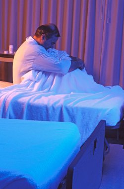 Depresyondaki bir hasta hastane yatağında oturuyor..