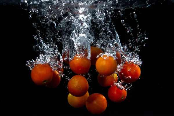 cherry tomatoes splashing in water