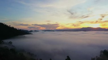 aerial view scenery sunrise above the mountain in tropical rainforest.slow floating fog blowing cover on the mountain look like as a sea of mist. beautiful sunrise in the mist background.