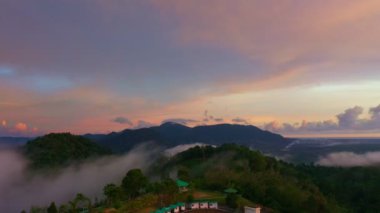 aerial view scenery sunrise above the mountain in tropical rainforest.slow floating fog blowing cover on the mountain look like as a sea of mist. beautiful sunrise in the mist background.