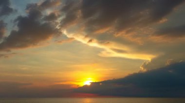 Karon plajı Phuket Tayland 'da gün batımında okyanus bulutlarının üzerindeki günbatımı manzarası okyanusu kaplıyor. video 4K. Gökyüzü arka planında Renkli Kırmızı Işık Sahnesi.