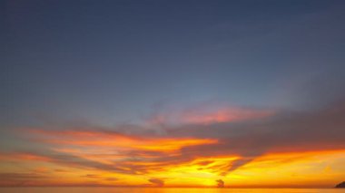 Karon plajı Phuket Tayland 'da gün batımında okyanus bulutlarının üzerindeki günbatımı manzarası okyanusu kaplıyor. video 4K. Gökyüzü arka planında Renkli Kırmızı Işık Sahnesi.