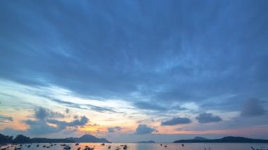 Karon plajı Phuket Tayland 'da gün batımında okyanus bulutlarının üzerindeki günbatımı manzarası okyanusu kaplıyor. video 4K. Gökyüzü arka planında Renkli Kırmızı Işık Sahnesi.