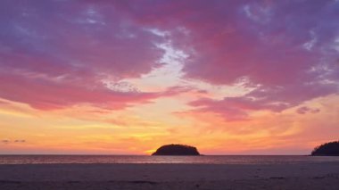 Akşamları adanın yukarısında gökyüzünde renkli bulutlar. Sarı güneş renkli gökyüzünde Kata plajı Phuketi 'ndeki Pu adasının arkasında batıyor. Adanın arka planında mor bulutlar..