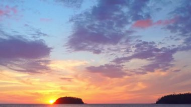 Akşamları adanın yukarısında gökyüzünde renkli bulutlar. Sarı güneş renkli gökyüzünde Kata plajı Phuketi 'ndeki Pu adasının arkasında batıyor. Adanın arka planında mor bulutlar..