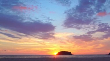 Akşamları adanın yukarısında gökyüzünde renkli bulutlar. Sarı güneş renkli gökyüzünde Kata plajı Phuketi 'ndeki Pu adasının arkasında batıyor. Adanın arka planında mor bulutlar..
