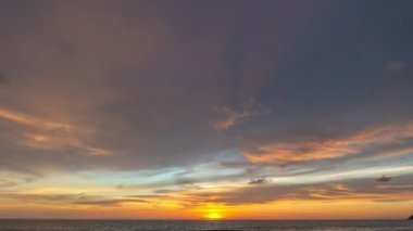 Karon plajı Phuket Tayland 'da gün batımında okyanus bulutlarının üzerindeki günbatımı manzarası okyanusu kaplıyor. video 4K. Gökyüzü arka planında Renkli Kırmızı Işık Sahnesi.