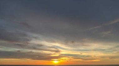 Karon plajı Phuket Tayland 'da gün batımında okyanus bulutlarının üzerindeki günbatımı manzarası okyanusu kaplıyor. video 4K. Gökyüzü arka planında Renkli Kırmızı Işık Sahnesi.