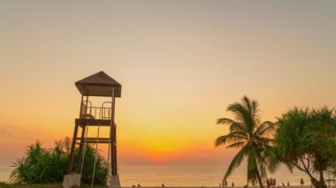 timelapse colorful bright sky of sunset behind lifeguard tower at Karon beach.Karon beach is broad and long Sand and beautiful beach.4k stock footage video in travel concept. bright sky background