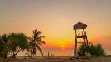 timelapse colorful bright sky of sunset behind lifeguard tower at Karon beach.Karon beach is broad and long Sand and beautiful beach.4k stock footage video in travel concept. bright sky background