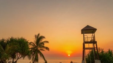 timelapse colorful bright sky of sunset behind lifeguard tower at Karon beach.Karon beach is broad and long Sand and beautiful beach.4k stock footage video in travel concept. bright sky background