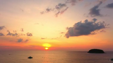 Kata sahilinin üstündeki hava manzarası. Günbatımında yeşil denizde yumuşak dalgalar. Seyahat konseptindeki video görüntüleri. Arka planda bulutlar. Turistler plaj boyunca denizde eğleniyorlar.. 