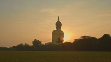 Muang Ang Thong Tayland 'da Tayland' ın büyük Buda 'sının önünde gün doğumu. Dünyanın en büyük Buda heykeli pirinç tarlalarıyla çevrili olarak uzaktan görülebilir..