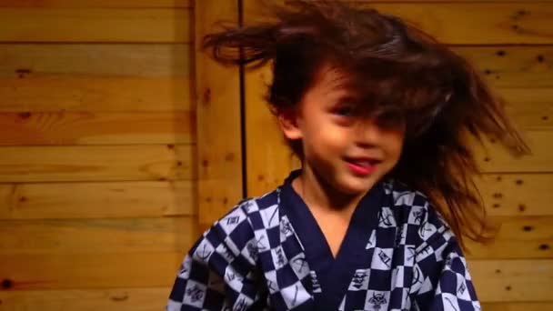 Een Schattig Jongetje Zit Een Houten Kamer Zwaaiend Met Zijn — Stockvideo