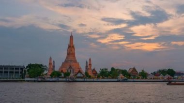 time lapse scenery sunset at large illuminated temple Wat Arun ratchawararam the biggest and tallest pagoda in the world beside Chaophraya river Bangkok Thailand.reflection of beautiful pagoda.