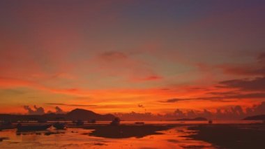 Gün doğumunda adanın üzerinde renkli parlak kırmızı gökyüzü. Parlak kırmızı gökyüzü arka plan. Rawai plajı Phuket4K çözünürlüklü güzel manzara..