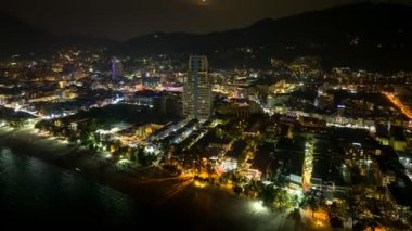 Patong sahilinin üzerinde gece görüş açısı yükseliyor. Plaj boyunca ve Patong sahilindeki çeşitli kasabalarda parlayan ışıklar. Yaratıcı doğa ve seyahat kavramı. dolunay arkaplanı.