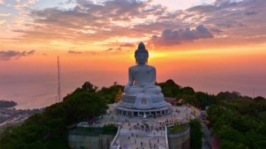 Hava manzaralı Phuket Büyük Buda güzel bir gün batımında. Güneş bulutların arasından parlıyor okyanus yüzeyine çarpıyor. Heykelin güzelliği büyüleyici doğayla mükemmel bir şekilde örtüşüyor..