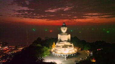 Phuket Büyük Buda 'da alacakaranlıkta inanılmaz bir kızıl gökyüzü. Kumsal boyunca ve Phuket Adası etrafındaki çeşitli kasabalarda parlayan ışıklar. yaratıcı seyahat konsepti. çarpıcı kırmızı gökyüzü arkaplanı.
