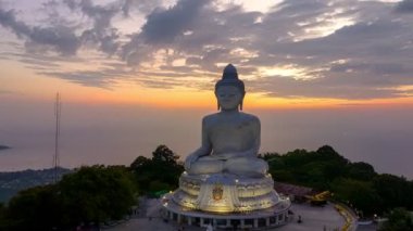  Phuket Büyük Buda 'nın güzel günbatımında gökyüzü yanılıyor güneş bulutların arasından parlıyor okyanus yüzeyine çarpıyor. Heykelin güzelliği büyüleyici doğayla mükemmel bir şekilde örtüşüyor. Bulut manzarası..