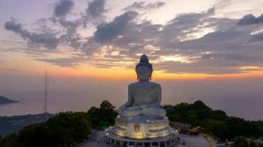  Phuket Büyük Buda 'nın güzel günbatımında gökyüzü yanılıyor güneş bulutların arasından parlıyor okyanus yüzeyine çarpıyor. Heykelin güzelliği büyüleyici doğayla mükemmel bir şekilde örtüşüyor. Bulut manzarası..